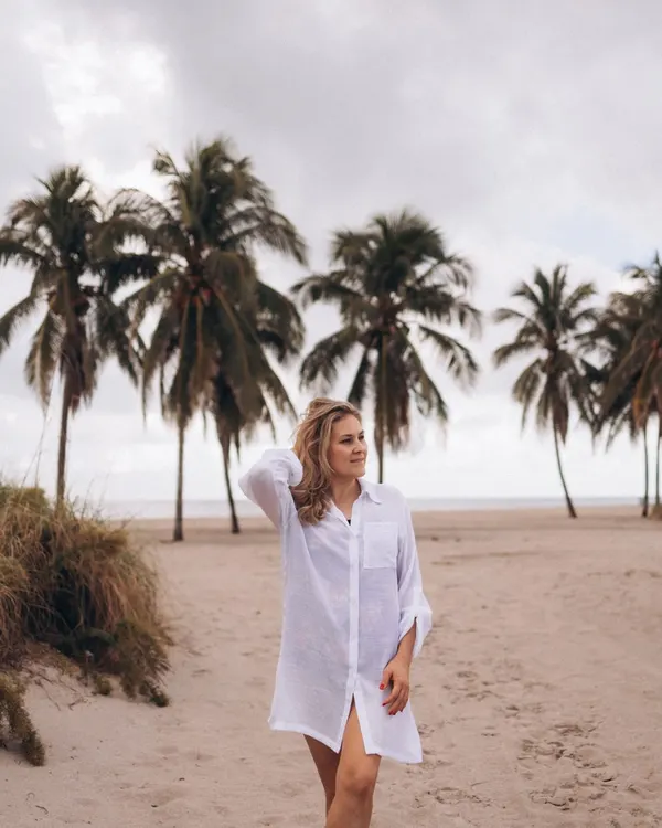 Woman walking on a beach in the white beach cover shirt