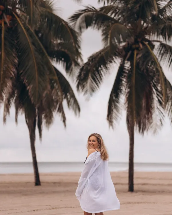 The white beach cover shirt on the beach, with palm trees behind