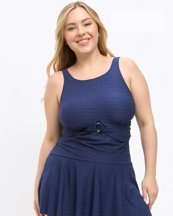 Woman wearing the Donna mastectomy swim dress in navy, with a ring detail at the waist and a flared skirt