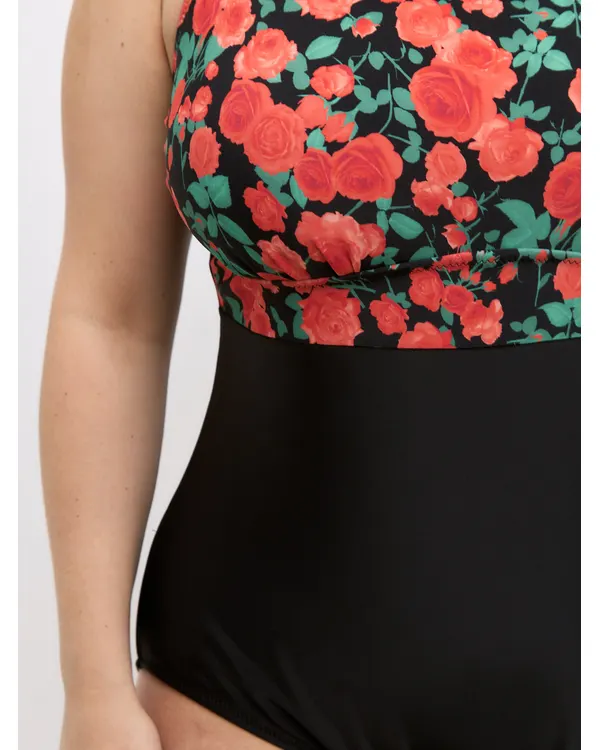 Close-up of the Lida swimsuit where the rose-print bodice meets the black body